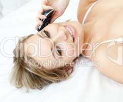 Charming woman talking on phone lying on a bed