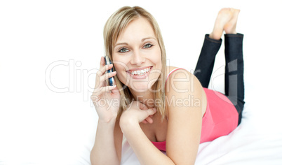 Cheerful woman talking on phone lying on a bed