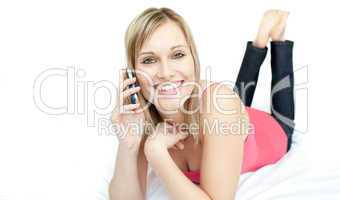 Cheerful woman talking on phone lying on a bed