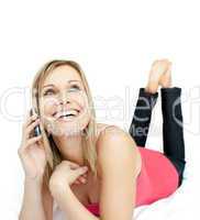 Jolly woman talking on phone lying on a bed