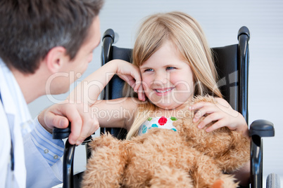 Laughing little girl sitting on the wheelchair