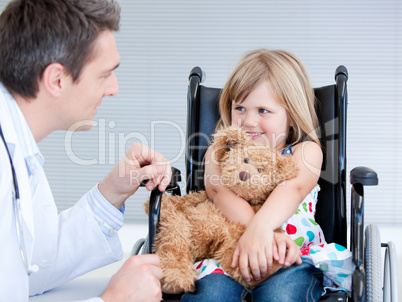 Smiling little girl sitting on the wheelchair lokking at the doc