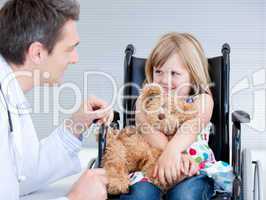 Smiling little girl sitting on the wheelchair lokking at the doc