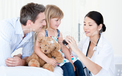 Concentrated asian female doctor giving syrup to a little girl