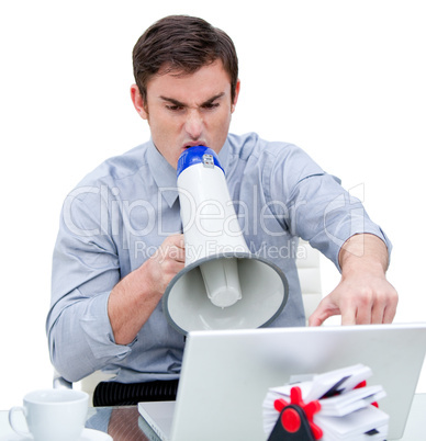Furious businessman yelling through a megaphone sitting at his d