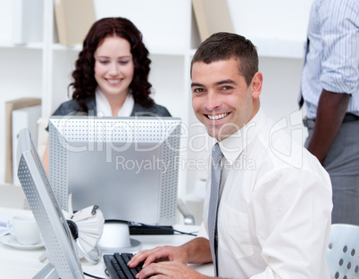 Smiling young business people working at computers
