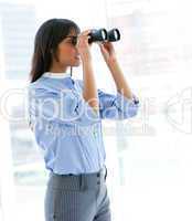 Confident female executive looking through binoculars