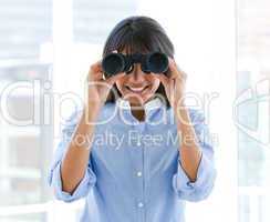 Positive female executive looking through binoculars