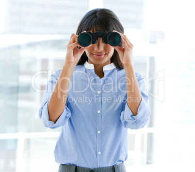 Assertive female executive looking through binoculars