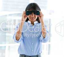 Assertive female executive looking through binoculars
