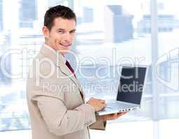 Positive businessman using a laptop standing