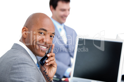 Happy businessman on phone and his colleague working at a comput