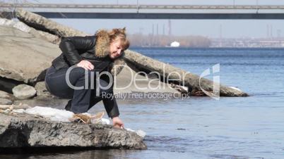 woman plays water on river bank.