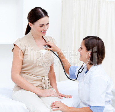 Female doctor examining  a smiling female patient with his steth