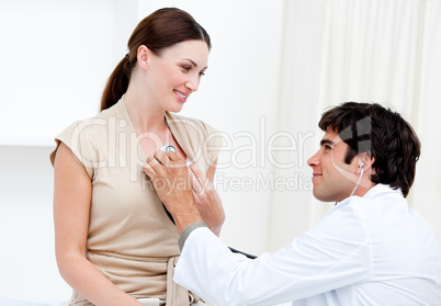 Male doctor examining  a smiling female patient with his stetho