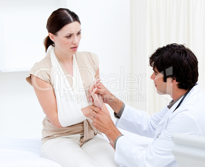 Young male doctor examining the female patient by taking her arm