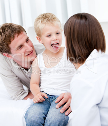Cute female doctor examining a little boy with his father