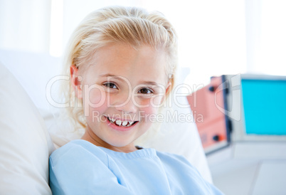 Sick little girl sitting on a hospital bed