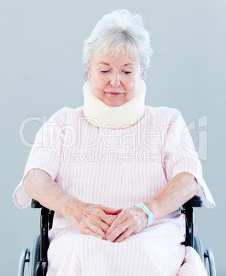 Upset senior woman with a neck brace sitting on a wheelchair