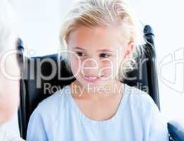 Blond little girl sitting on a wheelchair