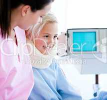 Smiling little girl with a neck brace sitting on a hospital bed