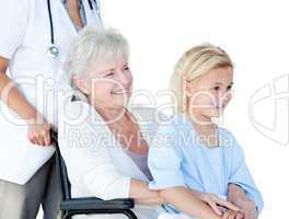 Smiling senior woman sitting on a wheelchair with her granddaugh