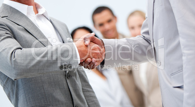 Businessmen shaking hand in front of their colleagues