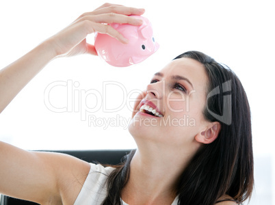 Cute businesswoman looking at a piggybank