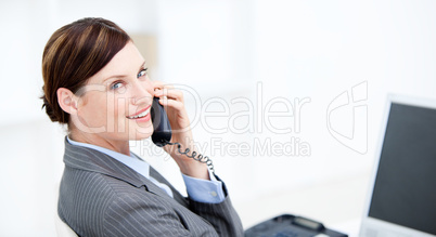 Smiling businesswoman on phone sitting at her desk