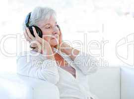 Charming senior woman listening music with headphones