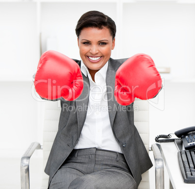Attractive businesswoman wearing boxing gloves sitting at her de
