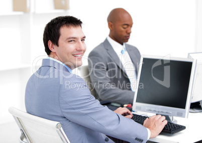 Happy young businessmen working at computers