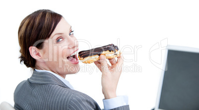 Delighted businesswoman eating a chocolate eclair