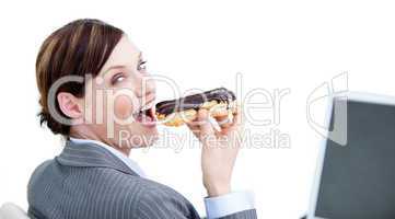 Delighted businesswoman eating a chocolate eclair