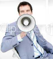 Furious young businessman yelling through a megaphone