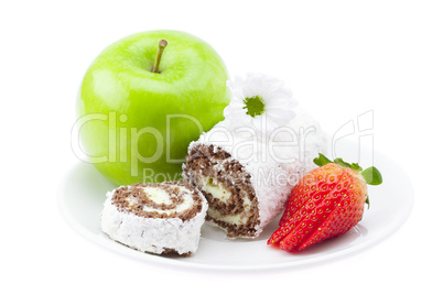 cake roll, apple and strawberry on a plate isolated on white