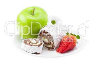 cake roll, apple and strawberry on a plate isolated on white