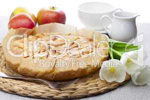 apple pie, tulips, apples and glassware on a wicker mat