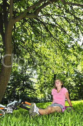 Teenage girl relaxing in a park with her bicycle