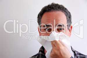 Sick man blowing nose