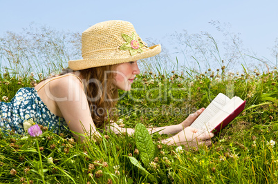 Young girl reading book in meadow