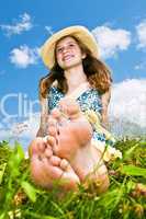 Young barefoot girl sitting in meadow
