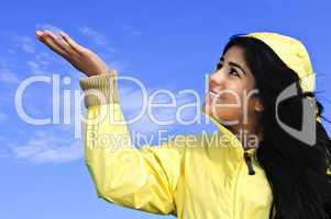 Beautiful young woman in raincoat checking for rain