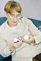 Elderly woman reading pill bottles