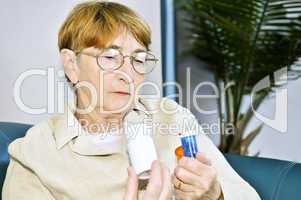 Elderly woman reading pill bottles