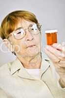 Elderly woman reading pill bottles