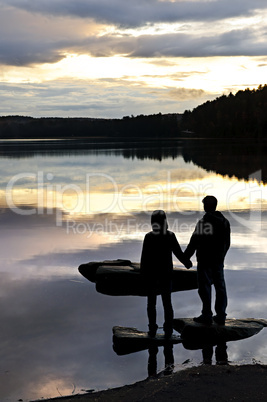 Silhouette of people watching sunset at lake