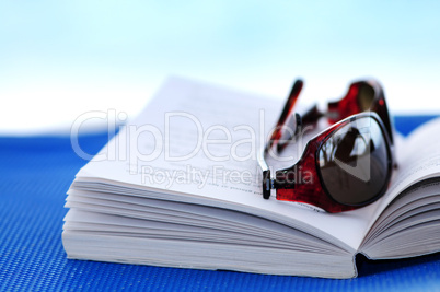 Sunglasses and book on beach chair