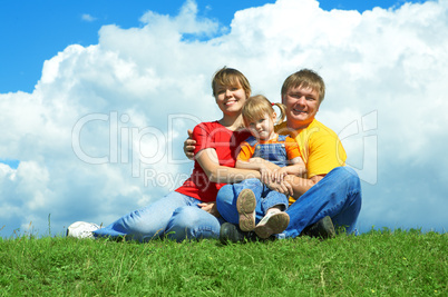 happy family sit on green grass under sky