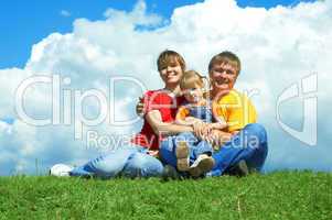 happy family sit on green grass under sky